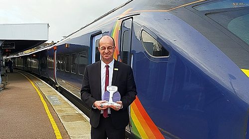 Lee in uniform standing next to a high speed train
