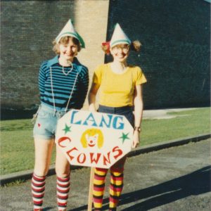 Two female students dressed as clowns holding the Lang team sign for the Christ Church It's a Knockout competition.